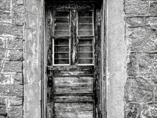 A vertical grayscale shot of a door at the Eastern State Penitentiary in Philadelphia, Pennsylvania